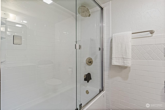 bathroom with bath / shower combo with glass door