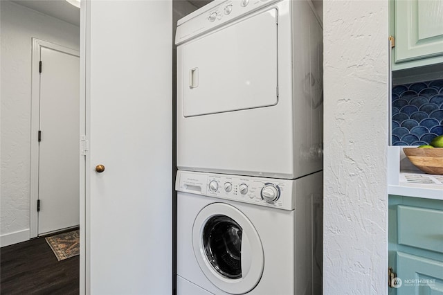 clothes washing area with dark hardwood / wood-style flooring and stacked washer / dryer