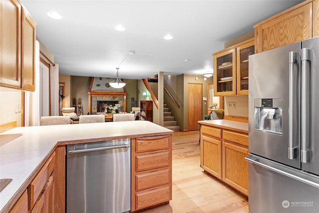 kitchen featuring stainless steel appliances, light hardwood / wood-style floors, and hanging light fixtures