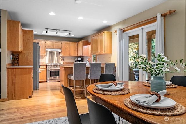 dining area featuring sink, light hardwood / wood-style flooring, and track lighting