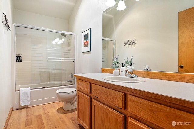 full bathroom featuring vanity, wood-type flooring, toilet, and combined bath / shower with glass door