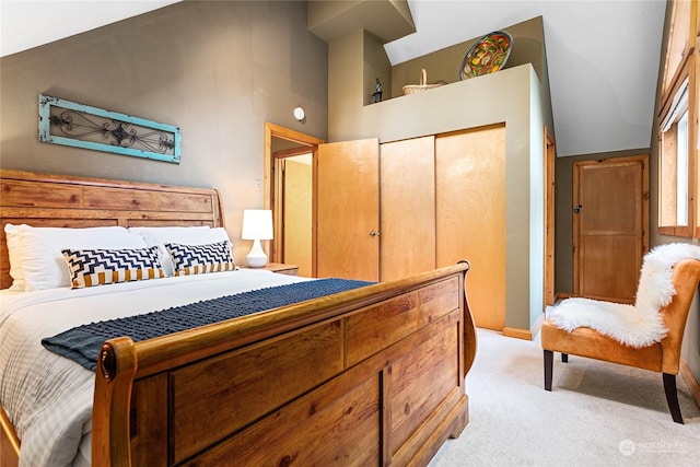 bedroom featuring a closet, high vaulted ceiling, and light carpet