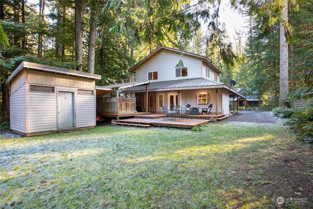 rear view of house featuring a yard, a storage unit, and a deck