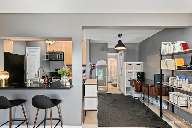 kitchen featuring pendant lighting, sink, light brown cabinetry, appliances with stainless steel finishes, and kitchen peninsula