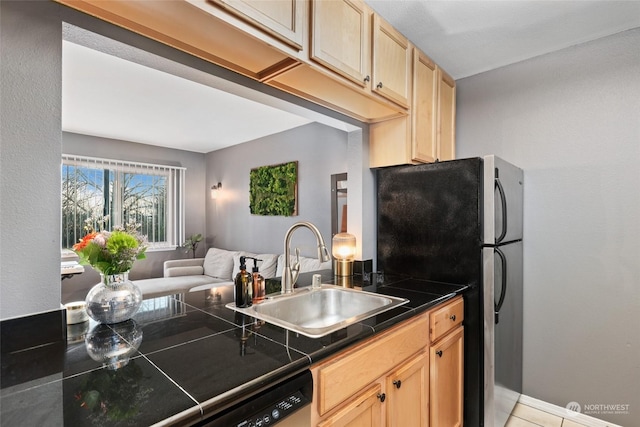 kitchen with light brown cabinetry, black fridge, stainless steel dishwasher, and sink