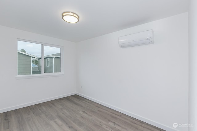 spare room featuring hardwood / wood-style floors and a wall mounted air conditioner