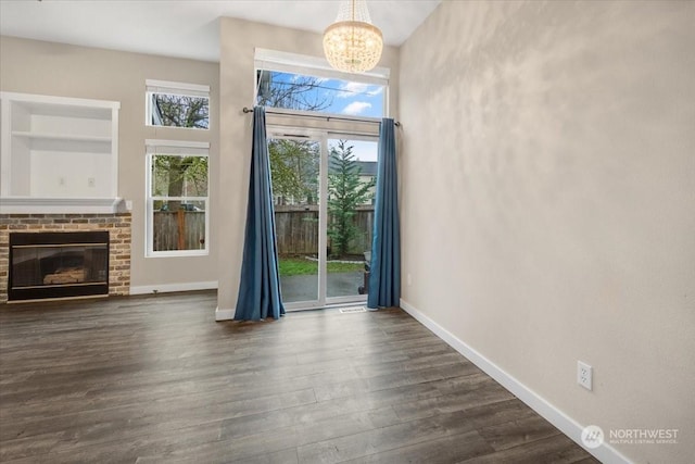 unfurnished living room with dark hardwood / wood-style floors, an inviting chandelier, and a fireplace