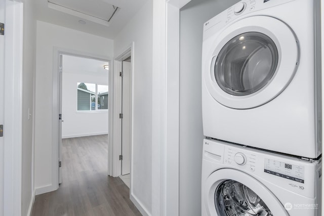 laundry area with stacked washing maching and dryer and dark hardwood / wood-style floors