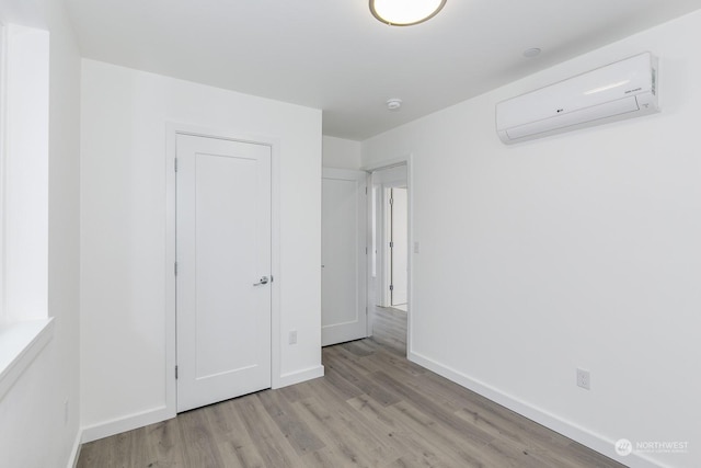 unfurnished bedroom featuring a wall mounted air conditioner and light hardwood / wood-style flooring