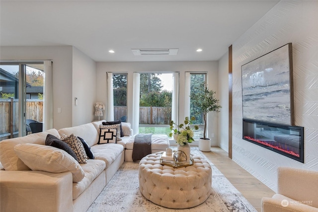 living room with a wealth of natural light, a fireplace, and light hardwood / wood-style flooring