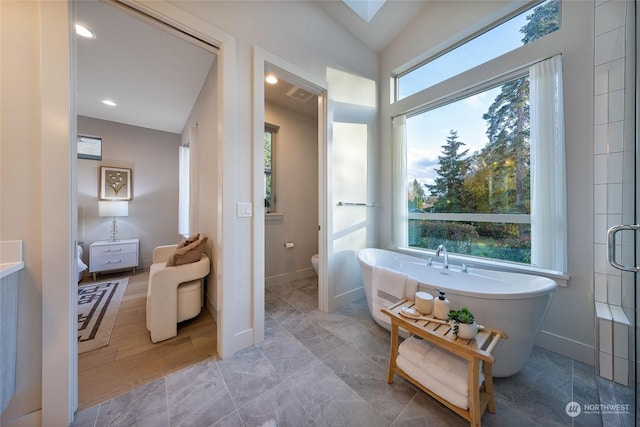 bathroom with shower with separate bathtub, toilet, plenty of natural light, and lofted ceiling