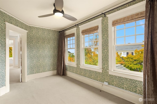 unfurnished room featuring ceiling fan, carpet floors, ornamental molding, and a healthy amount of sunlight