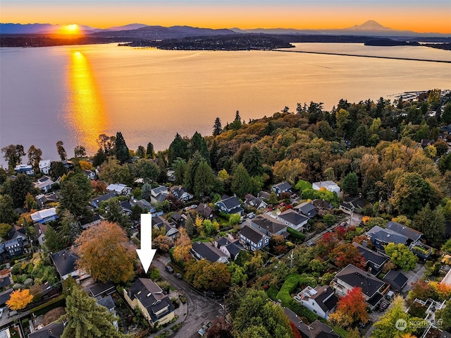 aerial view at dusk featuring a water and mountain view