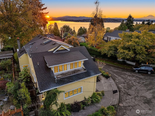 aerial view at dusk featuring a water and mountain view