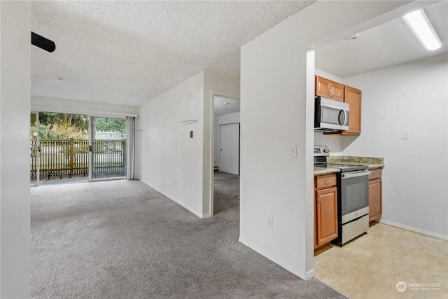 kitchen featuring a textured ceiling, stainless steel appliances, and light colored carpet