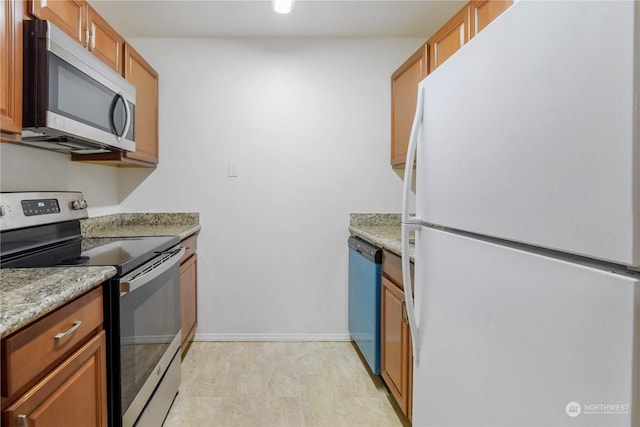 kitchen featuring appliances with stainless steel finishes, light hardwood / wood-style flooring, and light stone counters