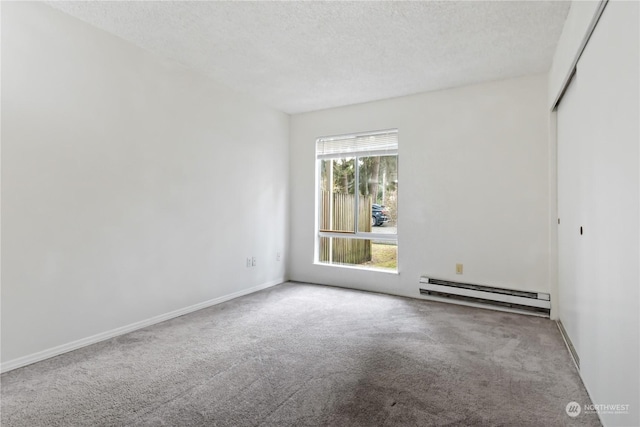 carpeted empty room featuring a textured ceiling and a baseboard heating unit