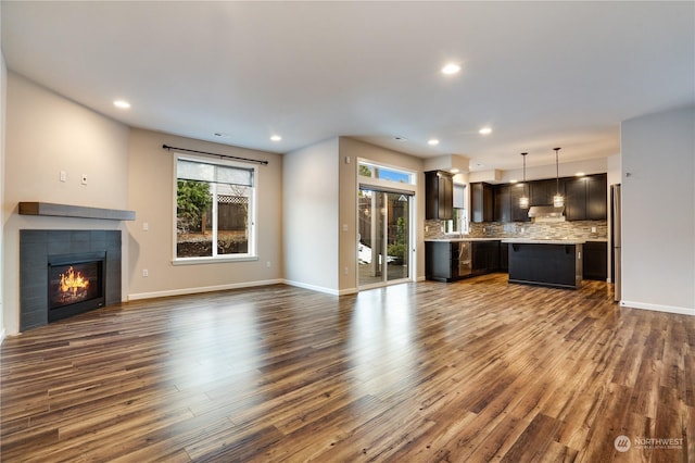 unfurnished living room featuring a tiled fireplace and dark wood-type flooring