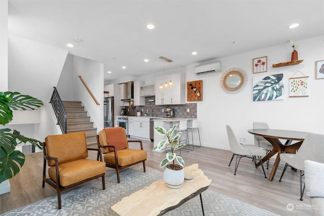 living room with a wall mounted air conditioner and light hardwood / wood-style flooring