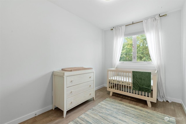 bedroom featuring wood-type flooring and a crib