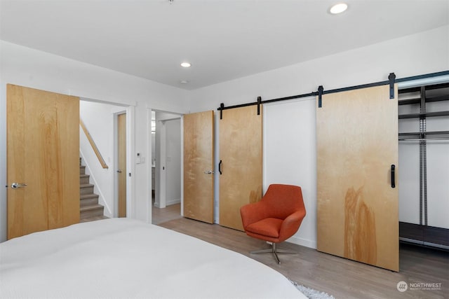 bedroom with hardwood / wood-style flooring, a barn door, and a closet