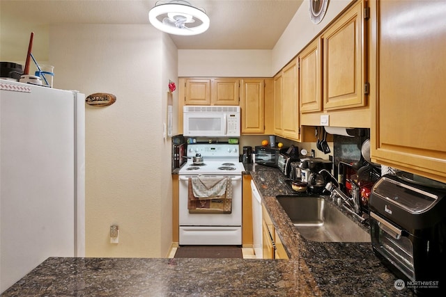 kitchen with sink, light brown cabinets, white appliances, and dark stone countertops