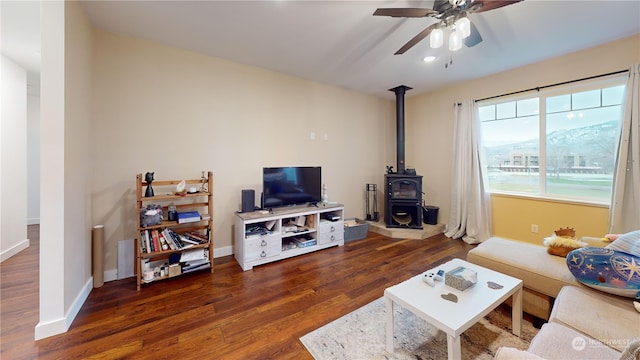 living room with a wood stove, ceiling fan, and dark hardwood / wood-style floors