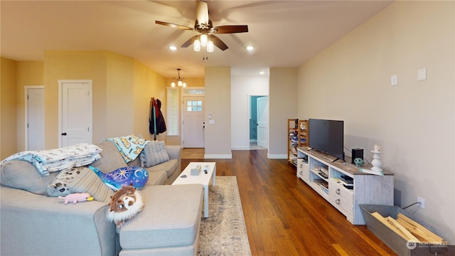 living room featuring ceiling fan with notable chandelier and dark hardwood / wood-style floors