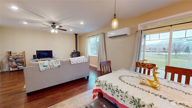 dining room featuring dark hardwood / wood-style floors, ceiling fan, a wood stove, and an AC wall unit