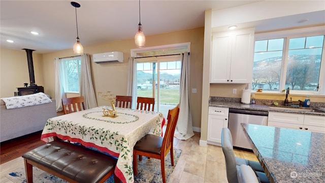 dining space with light hardwood / wood-style flooring, a wood stove, a wall mounted AC, and sink