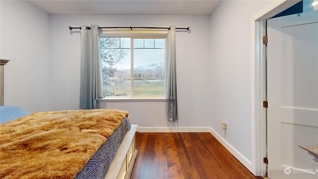 unfurnished bedroom with a mountain view, dark wood-type flooring, and multiple windows