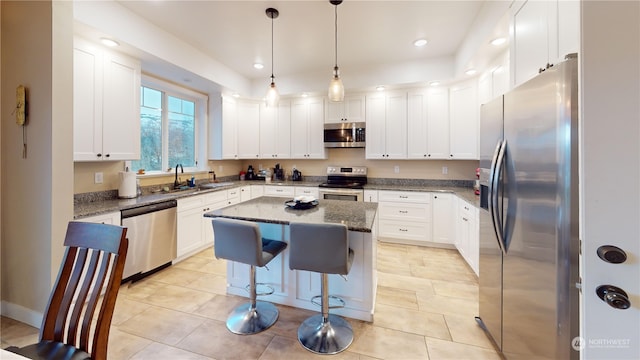 kitchen with a breakfast bar area, a center island, dark stone counters, and appliances with stainless steel finishes