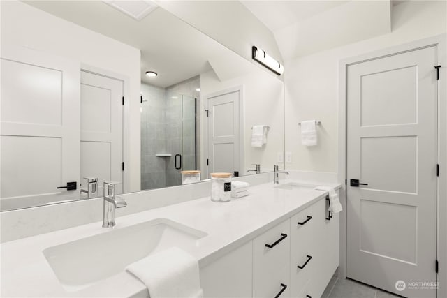 bathroom with vanity, a shower with shower door, tile patterned floors, and vaulted ceiling