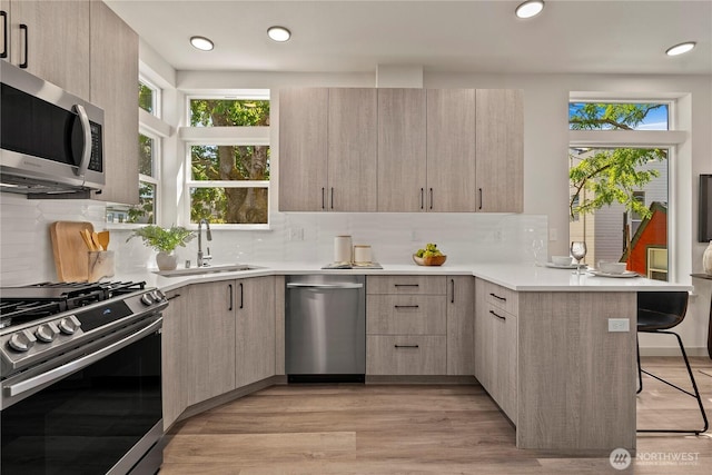 922B N 35th St, Seattle, WA 98103 - kitchen featuring appliances with stainless steel finishes, light brown cabinets, modern cabinets, a breakfast bar, and recessed lighting