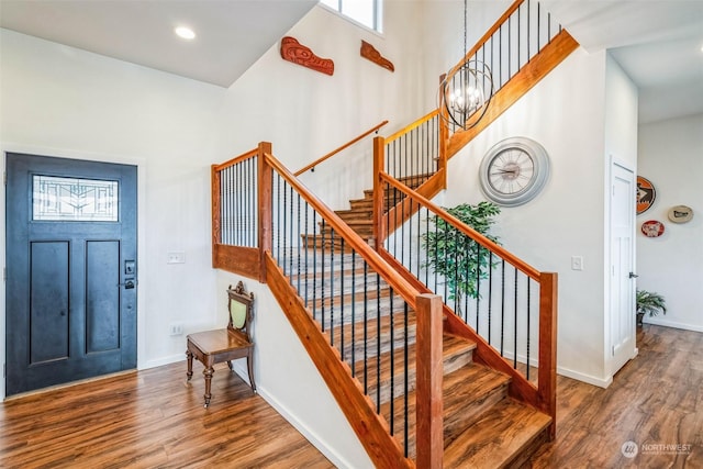 foyer with hardwood / wood-style flooring, a chandelier, and a towering ceiling