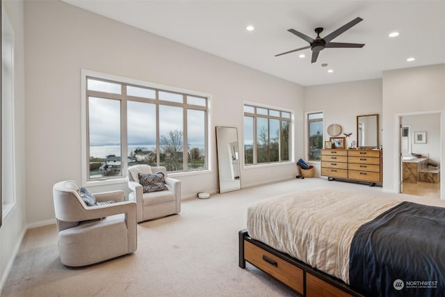 bedroom featuring light carpet, ceiling fan, and connected bathroom