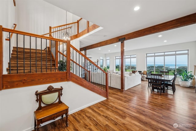 stairway with beamed ceiling, a chandelier, and hardwood / wood-style flooring