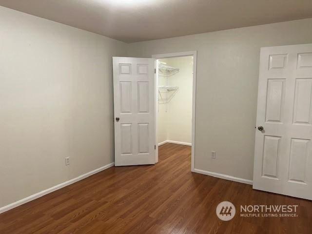 unfurnished bedroom with dark hardwood / wood-style floors, a walk in closet, and a closet