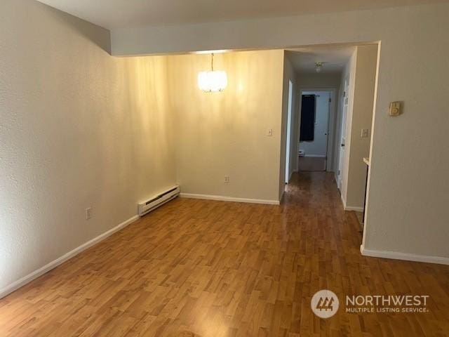 spare room with wood-type flooring and a baseboard radiator