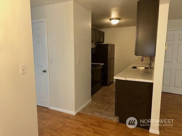 kitchen featuring dark brown cabinets, light wood-type flooring, sink, and black / electric stove