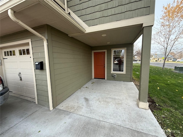 doorway to property with a garage and a lawn