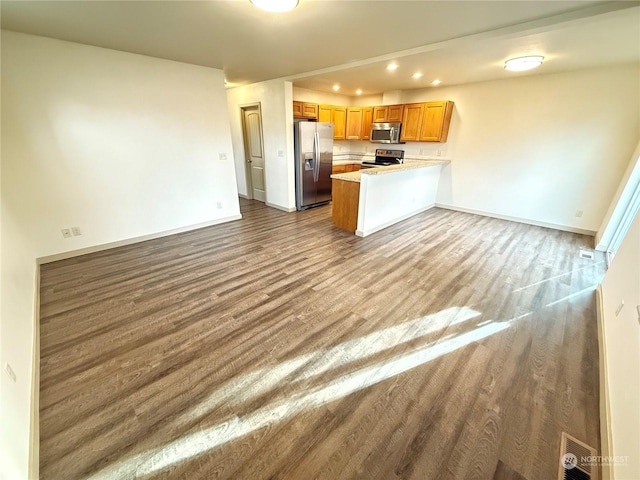 kitchen with kitchen peninsula, stainless steel appliances, and hardwood / wood-style flooring