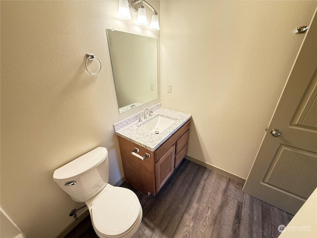 bathroom with hardwood / wood-style flooring, vanity, and toilet