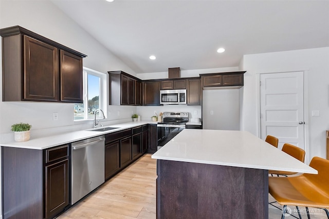 kitchen featuring a kitchen island, light countertops, appliances with stainless steel finishes, and a kitchen breakfast bar