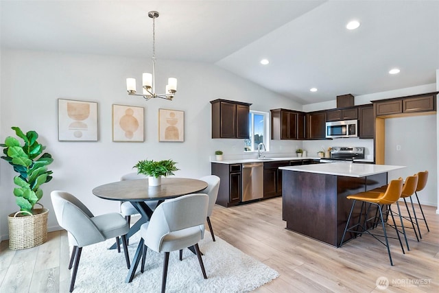 kitchen featuring light wood-style flooring, a center island, hanging light fixtures, light countertops, and appliances with stainless steel finishes