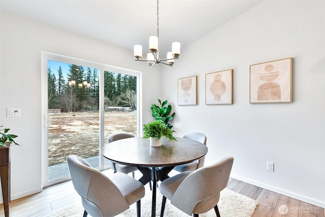 dining space featuring baseboards, an inviting chandelier, and light wood-style floors