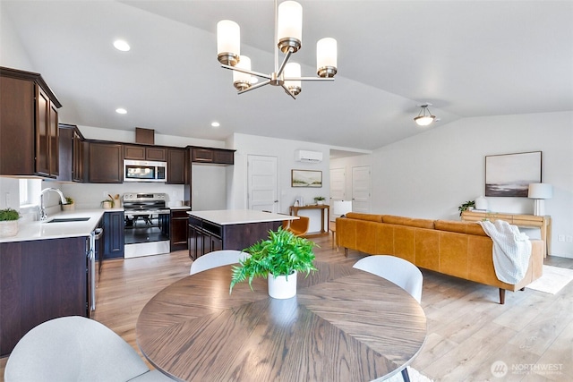 dining space featuring recessed lighting, lofted ceiling, light wood-style floors, and an inviting chandelier