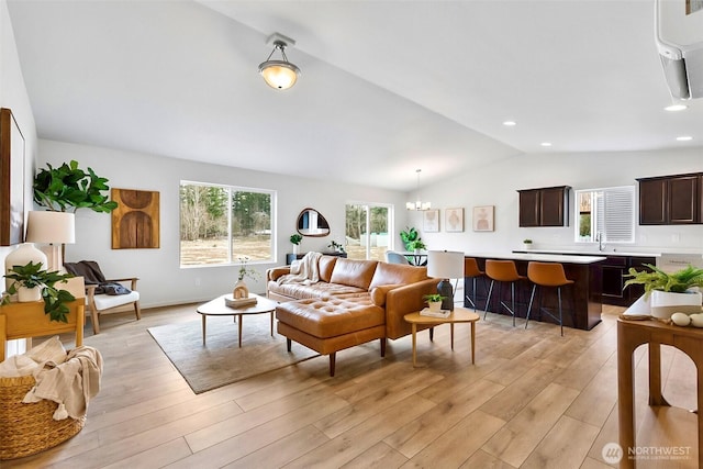 living area with light wood-style floors, a chandelier, recessed lighting, and vaulted ceiling