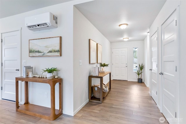 entrance foyer with baseboards, an AC wall unit, and light wood finished floors