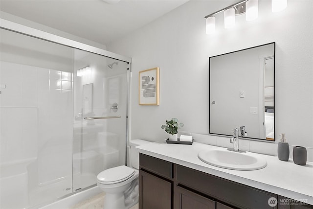 bathroom featuring a shower stall, toilet, and vanity